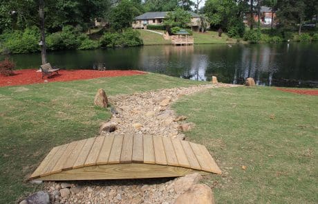 A small wooden bridge added to the pebbled waterway for soil erosion control in Aiken, SC