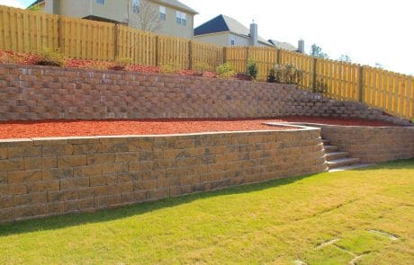 Retaining wall and landscaping against a wooden fence in Groovetown, GA